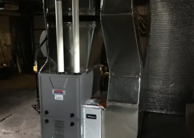A gas water heater located in a garage, featuring a cylindrical design and visible gas line connections.